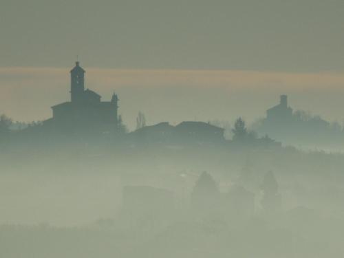 a foggy view of a hill with a church in the distance at Casa Rovelli in Alfiano Natta