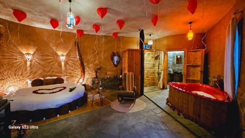 a bedroom with a bed and a tub with hearts on the wall at Панорама хаус Лещен и еко къщи Дървена и Землянка in Leshten