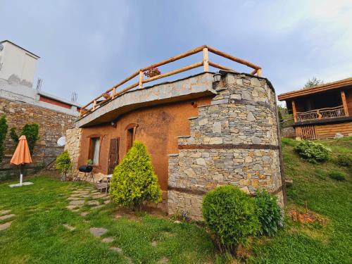 a stone building with a roof on top of it at Панорама хаус Лещен и еко къщи Дървена и Землянка in Leshten