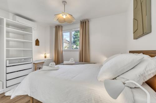 une chambre blanche avec un grand lit avec des oreillers blancs dans l'établissement Le Nordique II - Jolie vue - Clim - Netflix, à Aix-les-Bains