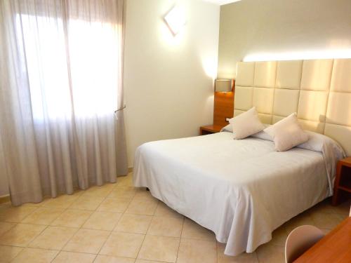 a bedroom with a white bed and a window at Hotel Kaly in Ventimiglia