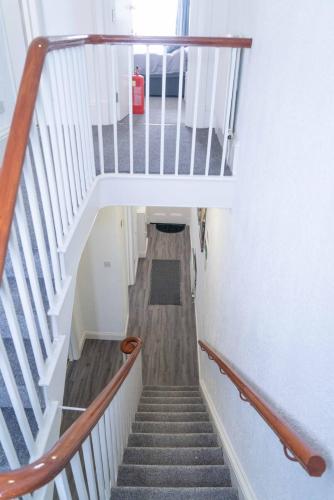 a staircase in a building with wooden floors and white rails at Carlisle Comfort Terrace in Carlisle