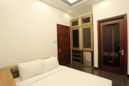 a bedroom with a white bed and a wooden door at Valentine Hotel in Ho Chi Minh City
