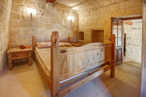 a bedroom with a large wooden bed in a stone wall at 5 Bedroom Farmhouse with Private Pool in Għarb