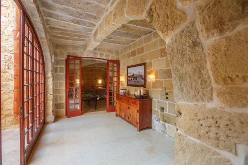 a hallway with red doors and a stone wall at 5 Bedroom Farmhouse with Private Pool in Għarb