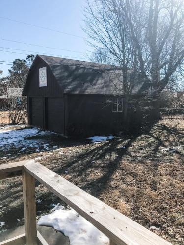 a small black shed with a wooden fence at Entire House in the Heart of NW AR with Office Space in Springdale