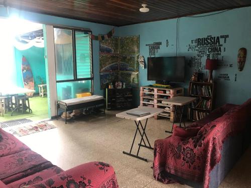 a living room with a couch and a flat screen tv at In the Wind Hostel and Guesthouse in San José