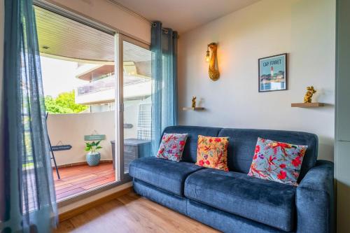 a blue couch in a living room with a sliding glass door at La perle du Bassin - Plage Pereire - Arcachon in Arcachon