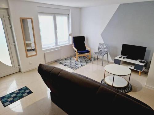 a living room with a couch and a table at Maison calme et toute équipée avec jardin in Maing