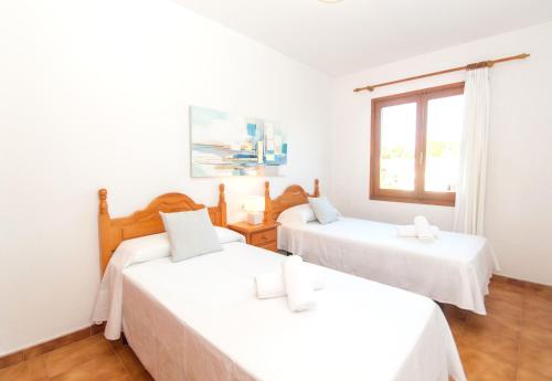 Dos camas en una habitación con ventana. en Villa Can Che by Sonne Villas, en Cala Galdana