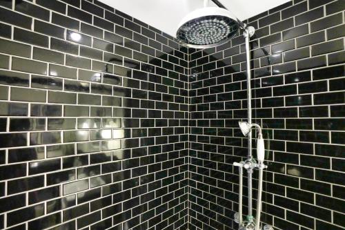 a black tiled bathroom with a shower with at Historic Wing in Tring: Cozy and Scenic in Tring