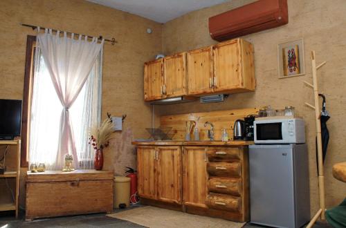 a kitchen with wooden cabinets and a refrigerator and a window at Панорама хаус Лещен и еко къщи Дървена и Землянка in Leshten