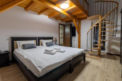 a bedroom with a large bed with white sheets and wooden ceilings at Pensiunea Aria Paltinis in Păltiniş