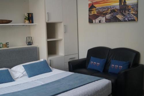 a bedroom with two beds with blue pillows and a chair at BGY Central Apartments in Bergamo