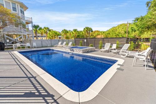 a swimming pool in a yard with chairs and a house at Long Bay Duplex in Myrtle Beach