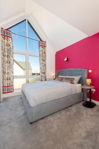 a bedroom with a bed and a pink wall at Beachwood Retreat in Sheringham
