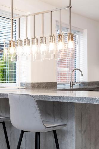 a kitchen with a sink and a counter with a chair at Beachwood Retreat in Sheringham