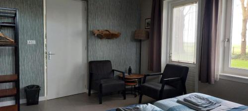 a room with two chairs and a table and a bed at Hoeve de Heemser Parel in Heemserveen