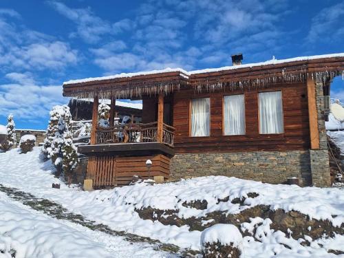 a log cabin with a balcony in the snow at Панорама хаус Лещен и еко къщи Дървена и Землянка in Leshten