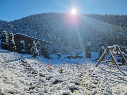 a snow covered mountain with a ski lift and a building at Панорама хаус Лещен и еко къщи Дървена и Землянка in Leshten