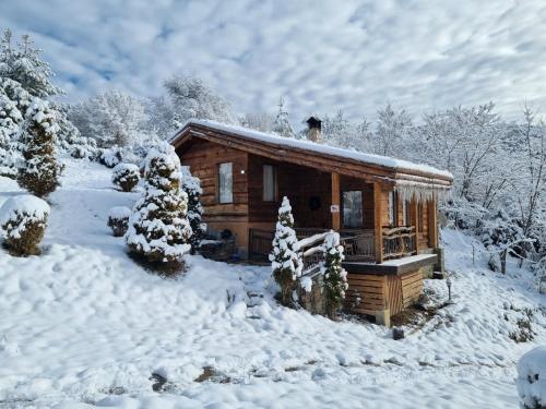 a log cabin with snow on the roof at Панорама хаус Лещен и еко къщи Дървена и Землянка in Leshten