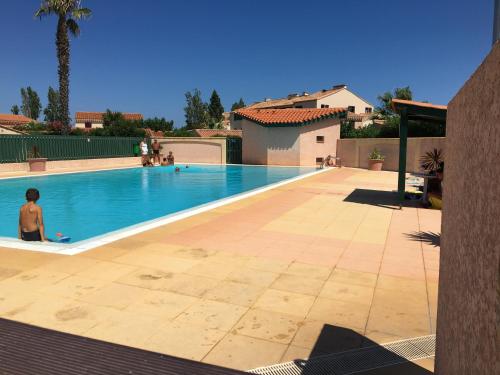 Un homme se tient à côté d'une piscine dans l'établissement Maison entière avec deux chambres et un jardin Dans résidence avec piscine et parking privé Proche de la mer et de la marina Au calme, à Saint Cyprien Plage