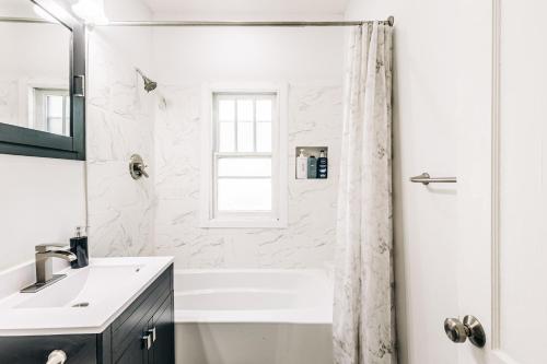 a white bathroom with a shower and a sink at Minnehaha Falls Hideaway in Minneapolis