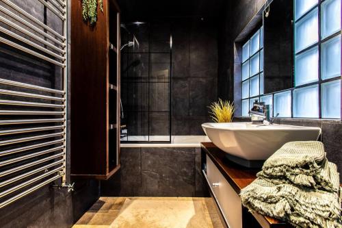 a bathroom with a white sink and a tub at Stay In Style At Olive 77 Book Your Trip Now in Hanwell