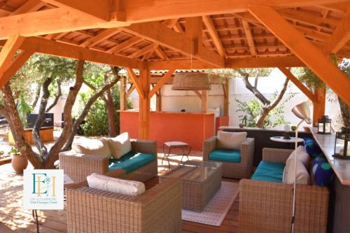 un patio avec des canapés et des chaises sous un pavillon dans l'établissement La Villa des Garrigues, à Saint-Bauzille-de-Montmel