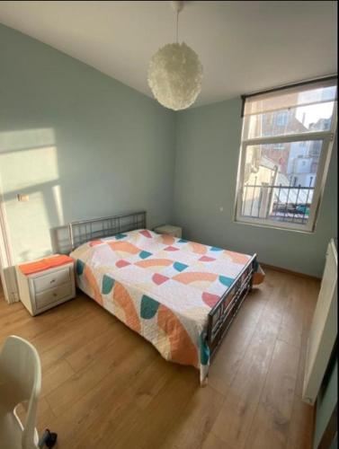 a bedroom with a bed with a comforter and two windows at Chambre confortable lits double schaarbeek premier étage in Brussels