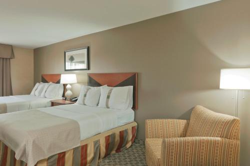 a hotel room with two beds and a chair at Holiday Inn Carbondale - Conference Center by IHG in Carbondale