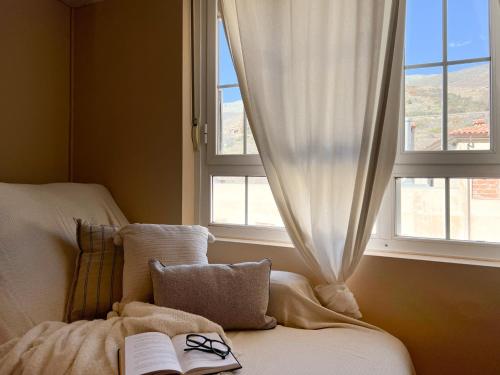 a bedroom with a bed with a book and a window at Alojamientos Abuelo Teófilo - Valle del jerte in Tornavacas