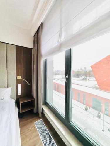 a bedroom with a large window with a view at Brabank Penthouse Old Town View, Sauna & Parking by Grandviewestate in Gdańsk