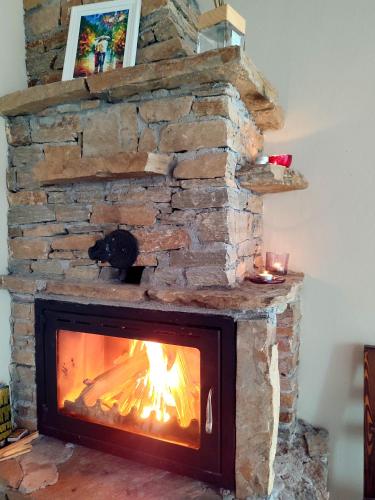 a stone fireplace with a fire in it at Панорама хаус Лещен и еко къщи Дървена и Землянка in Leshten