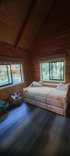 a large bed in a room with two windows at Quebrada del Chucao in Pucón