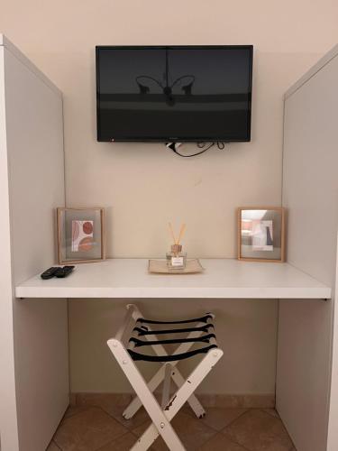 a desk with a television on a wall with two framed pictures at Residenza Fonticella in Rivisondoli