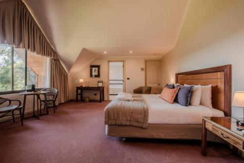 a bedroom with a large bed and a table and chairs at Hotel Puerta del Sur in Valdivia