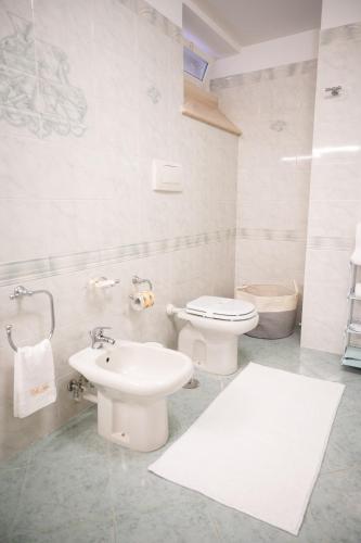 a white bathroom with a toilet and a sink at Villa Asia in Selva di Fasano