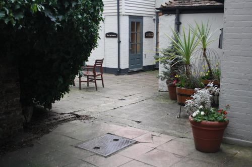 a patio with chairs and potted plants in front of a house at The Falstaff in Canterbury in Canterbury