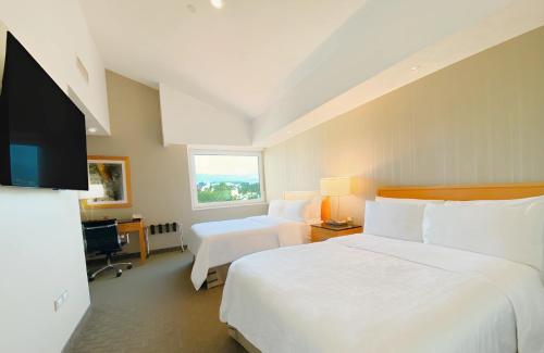 a hotel room with two beds and a flat screen tv at Holiday Inn Cuernavaca by IHG in Cuernavaca
