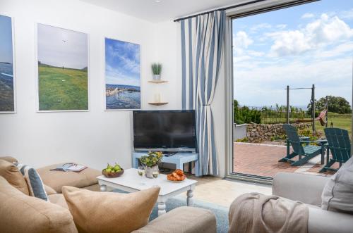 ペンザンスにあるSEA BREEZE - Stunning 6 Bedroom Eco Home with Sea Viewsのリビングルーム(テレビ、大きな窓付)