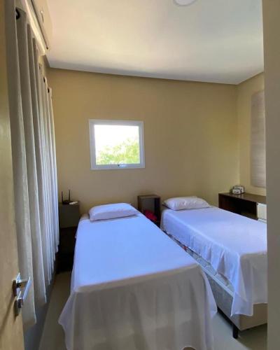 two beds in a room with a window at Casa de temporada Petrolina-PE in Petrolina