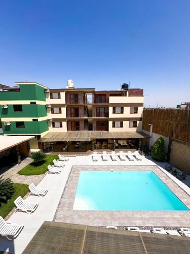 a swimming pool in front of a building at Apart-Hotel El Cañaveral in Chincha