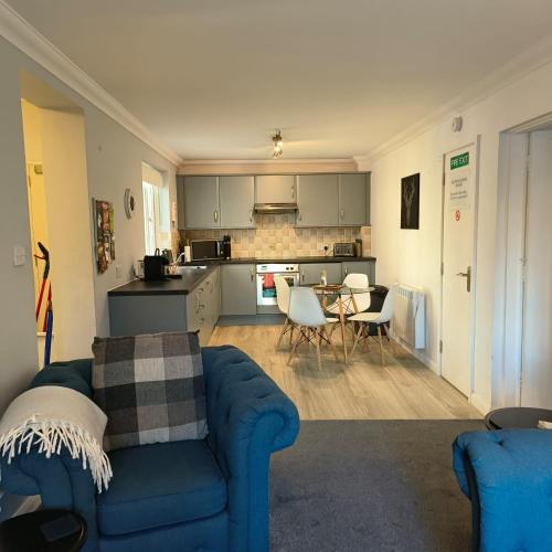 a living room with a blue couch and a kitchen at Ghyll Rigg in Bowness-on-Windermere