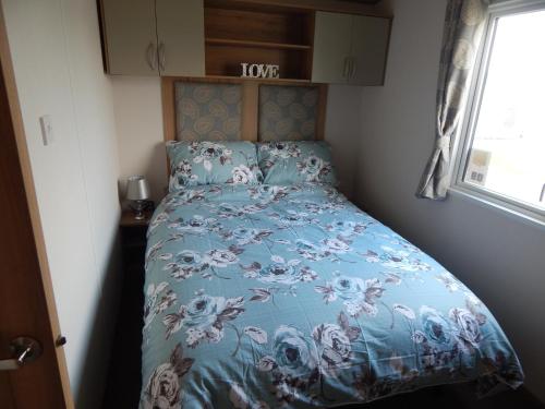 a bed in a small room with a blue comforter at AMC Flamingo Land Caravan, Motorhome & Campervan Hire in Kirby Misperton