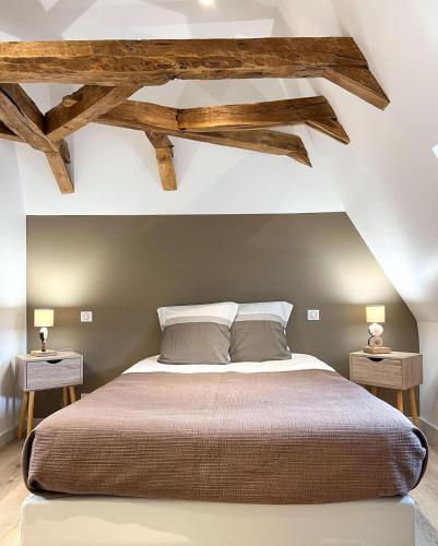 - une chambre avec un grand lit et des poutres apparentes dans l'établissement Domaine des 5M, Authenticité et Élégance au cœur du Cantal, à Velzic