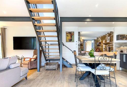 a spiral staircase in a living room with a table at Domaine des 5M, Authenticité et Élégance au cœur du Cantal in Velzic