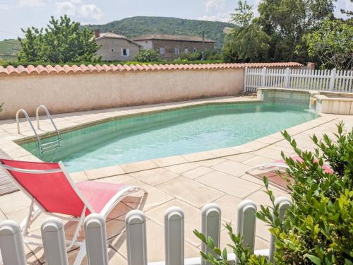 une chaise rouge assise à côté de la piscine dans l'établissement Panda Home, à Quincié-en-Beaujolais