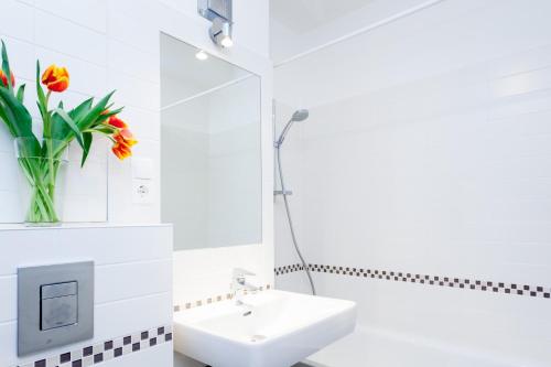 a white bathroom with a sink and a vase of flowers at The Maybach - rooftop living XBerg, 1BR, 1 living room, group & family friendly, 2 - 4 Guests in Berlin