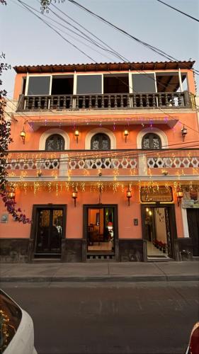 a pink building with a balcony on a street at Kolombrini Hotel in Guadalajara